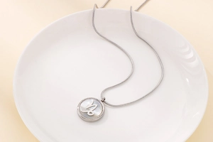 Macro shot of silver Capricorn zodiac necklace with mother of pearl inlay on ceramic tray