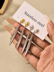 Detailed macro view of long teardrop stainless steel earrings in gold and silver finish