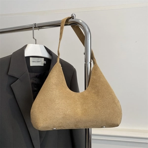 Detail of camel suede crescent bag with smooth zipper and bottom protective metal rivets