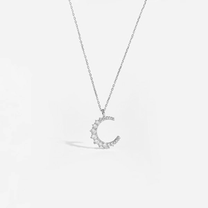 Macro shot of silver crescent moon pendant necklace featuring sparkling zircon stones