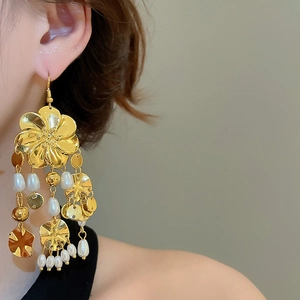 Detail von goldenen Vintage-Ohrringen mit eleganten Perlenquasten an einem Modell