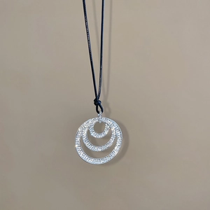 Close-up of triple circular pendant with sparkling crystal inlay on black leather cord