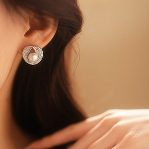 Détail d'une boucle d'oreille perle argentée et zircone sur un modèle féminin