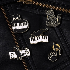 Close-up of enamel cat pins with musical notes on a black leather jacket texture