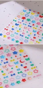 Macro detail of 3D embossed rainbow star and moon nail art stickers on transparent backing