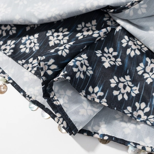Détail de l'imprimé fleuri sur la jupe avec perles de coquillage et couture précise