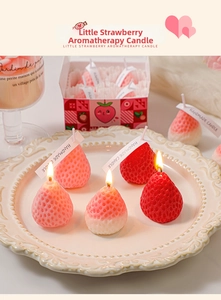 Macro shot of realistic strawberry scented candles with handmade labels in a porcelain dish