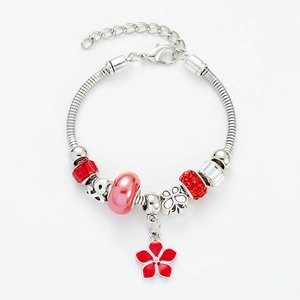 Detailed macro of silver charm bracelet with red floral pendants and crystal beads