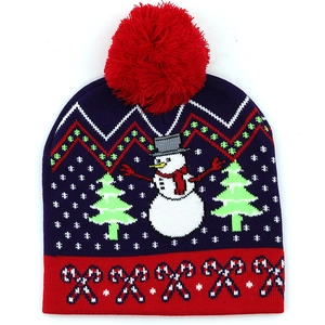 Details einer Strickmütze mit Schneemann-Muster, Weihnachtsbaum und roter Bommel