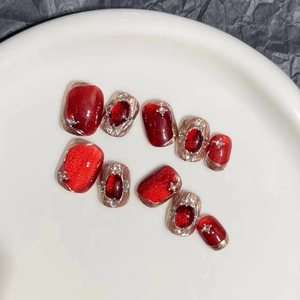 Macro detail of red glitter and gold gemstone-studded handmade press-on nails set