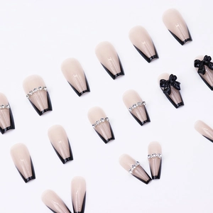 Long coffin nude press-on nails with black French tips, bows, and sparkling rhinestones