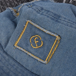 Detailed macro view of denim fabric with yellow rectangle patch and letter f embroidery