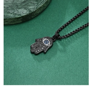 Detail view of a black Hamsa Hand pendant with zircon inlay and blue gemstone on a chain