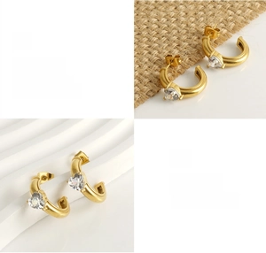 Détail de boucles d'oreilles C dorées avec zircon en forme de cœur et fini poli