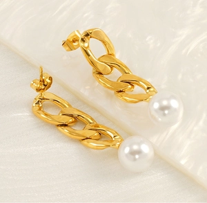 Detailed close-up of 18K gold plated chain earrings with large white pearls on white fabric