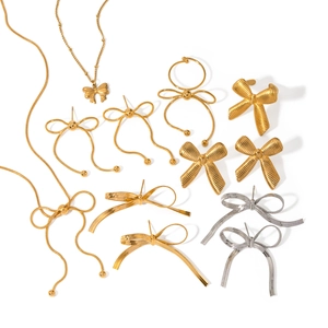 Collection of gold and silver bow-shaped necklaces, earrings, and rings on white background