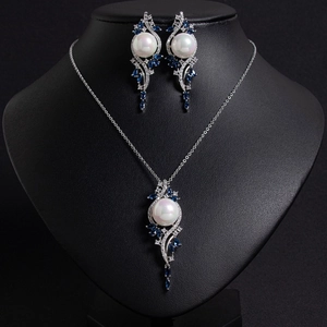 Detail of waterdrop pearl necklace and earrings set with blue gems on a black mannequin