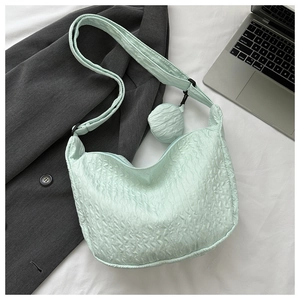 Detail of mint green puckered texture crossbody bag with strap and round pendant charm