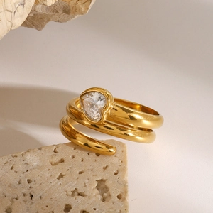 Elegant gold spiral ring with heart zircon stone on a natural stone background