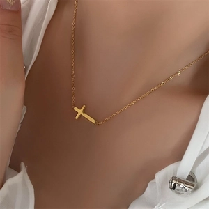 Close-up of gold stainless steel necklace with sideways cross pendant on model's neck