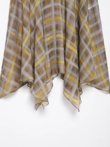 Close-up of lightweight plaid midi skirt featuring asymmetrical hem and yellow-grey tones