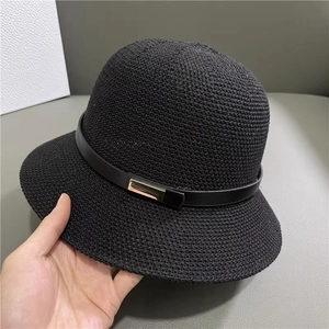 Détail de la texture tissée d'un chapeau de soleil noir en tricot avec boucle dorée chic