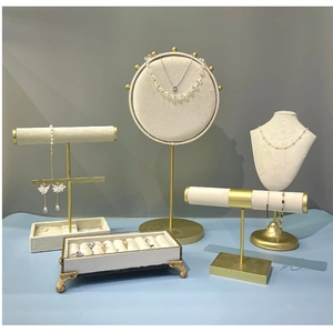 Ensemble détaillé de supports bijoux en métal doré et velours beige sur fond bleu