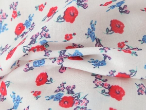 Detailed macro view of white floral fabric with red and blue embroidery patterns
