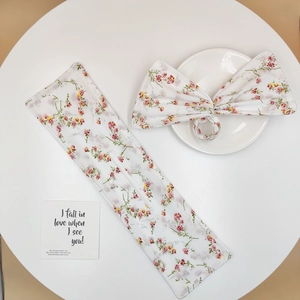 Detail of floral print hair bun maker and matching scrunchie on white display surface