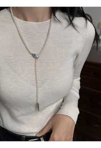 Detail of pearl necklace with green zircon snake clasp and silver cone pendant charm