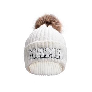 Detail of white ribbed knit hat with MAMA embroidery and brown faux fur pom-pom