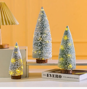 Close-up of three mini flocked cedar trees with warm LED lights on wooden bases