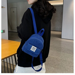 Blue corduroy mini backpack detail showing the Fashion Instinct patch and fabric texture