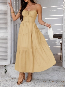 Detail view of apricot-colored midi dress featuring a stylish tiered skirt and spaghetti straps
