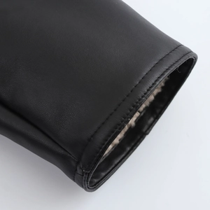 Dettaglio del polsino del cappotto in pelle nera con calda fodera in peluche e cuciture fini