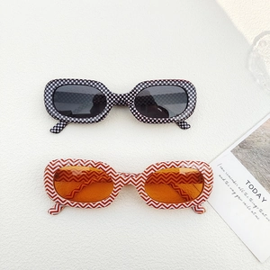 Oval fashion sunglasses in checkerboard and orange wave patterns on white background