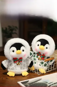 Detail of two Christmas penguin plush toys in knit sweaters with festive bells
