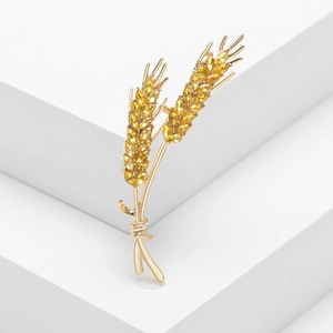 Close-up of golden wheat brooch with yellow marquise gems on white geometric steps