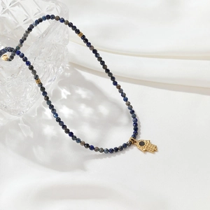 Elegant Lapis Lazuli necklace with golden beads and a Hamsa hand pendant on silk
