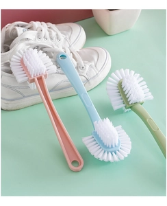 Detailed view of three long-handle cleaning brushes in pink, blue, and green for shoe care