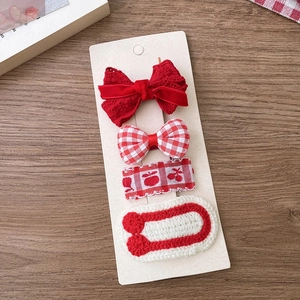 Detail of red fabric bow hair clips and knit floral hairpins on display card