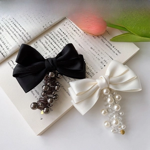 Detail of silk bow hair clips with hanging beads on an open book with tulips