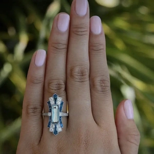 Art Deco ocean style ring with rectangular blue gemstone on a model's hand