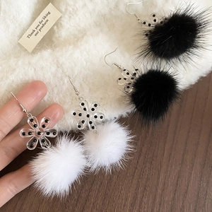 Detail view of fluffy faux fur ball earrings with acrylic snowflake flowers in black and white