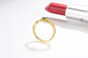 Detailed close-up of 14k gold plated ring with emerald gemstone and intricate engraving