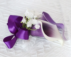 Detail of purple calla lily wrist corsage with silk ribbons and white floral accents