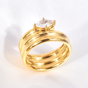 Macro shot of polished gold multi-layer ring with marquise cut zircon on white fabric