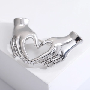 Macro close-up of a silver heart gesture brooch with a polished metallic finish