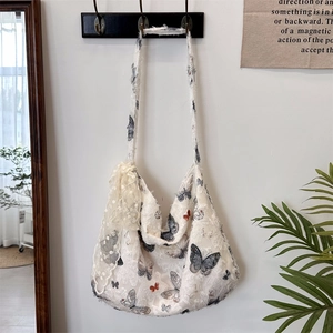 Detailed texture of white butterfly print hobo bag with lace trim and tassel edges