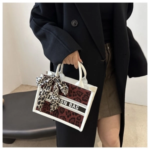 Detail of leopard print tote bag featuring FASHION BAG text and decorative silk scarf